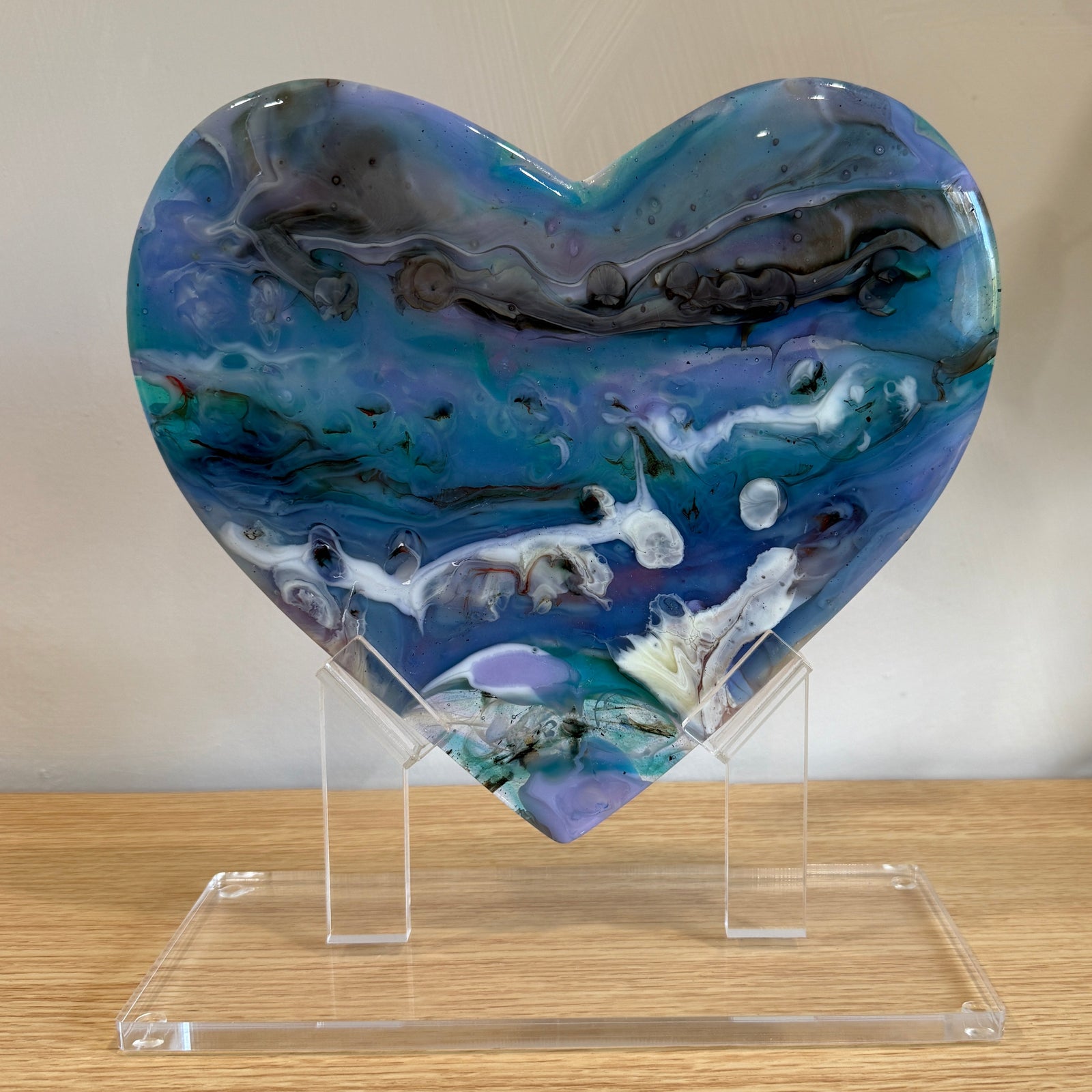 Heart-shaped decorative item with a multicolored pattern on a wooden surface.