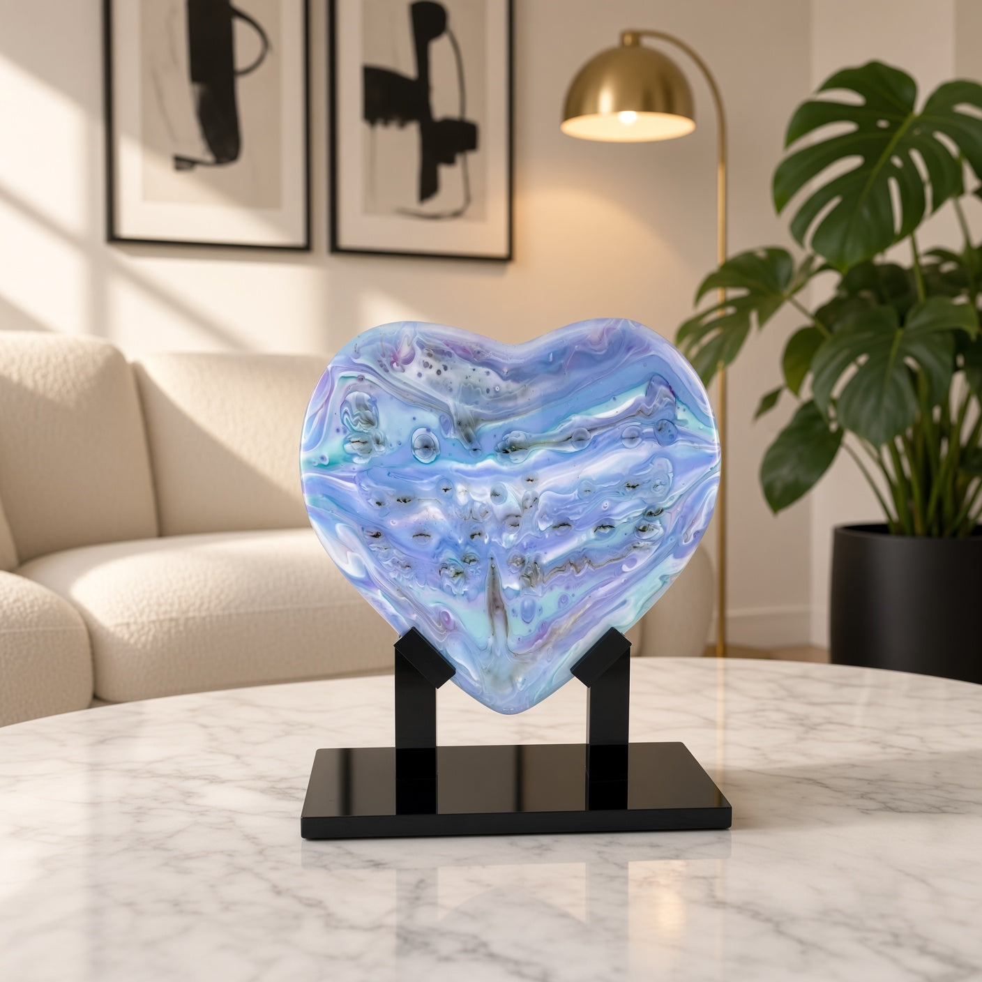 Pastel lavender and sky blue fused glass heart sculpture on black stand, staged on a marble table in a modern living room - handmade art glass gift