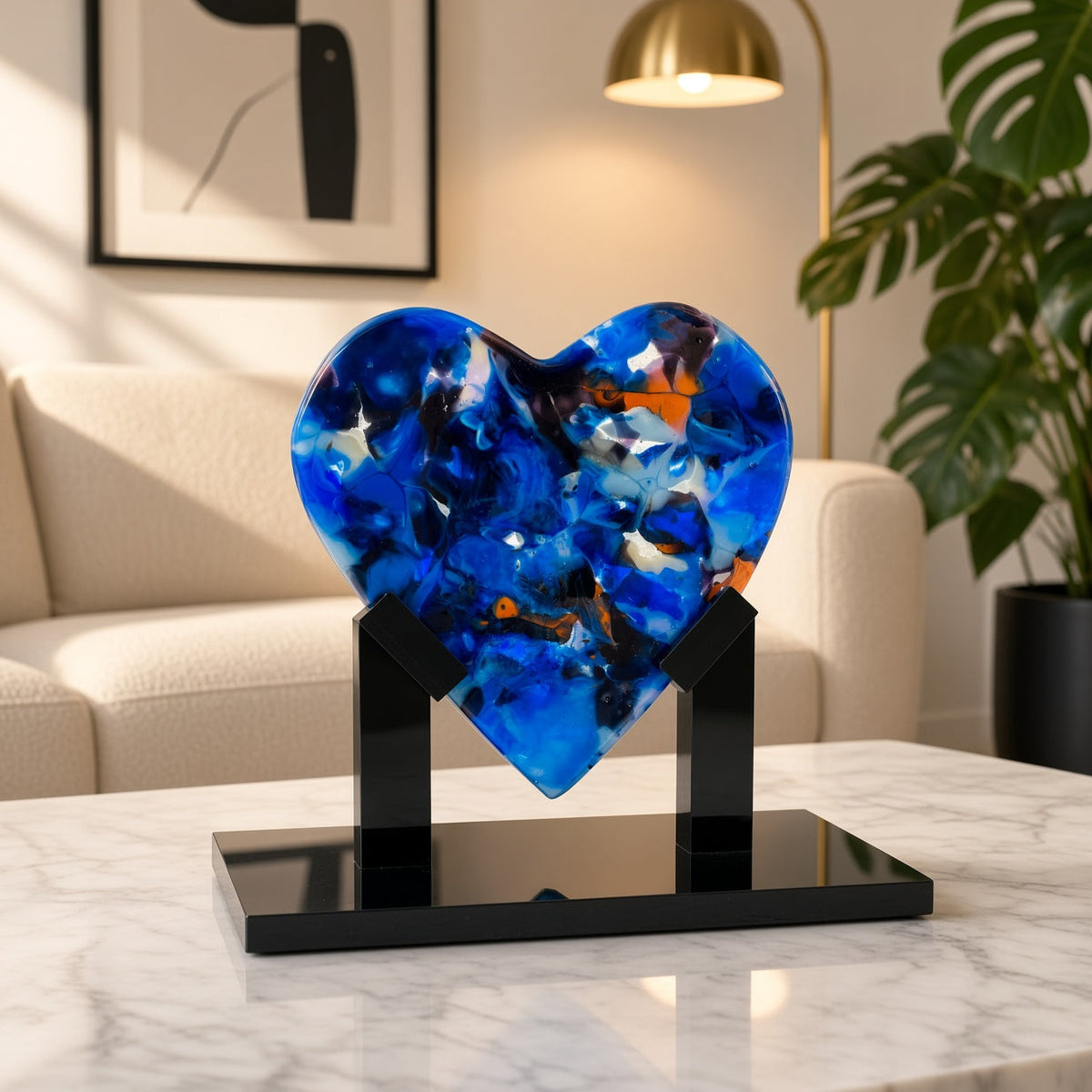 Navy blue and orange fused glass heart sculpture on black display stand, staged in a modern living room - handmade art glass gift