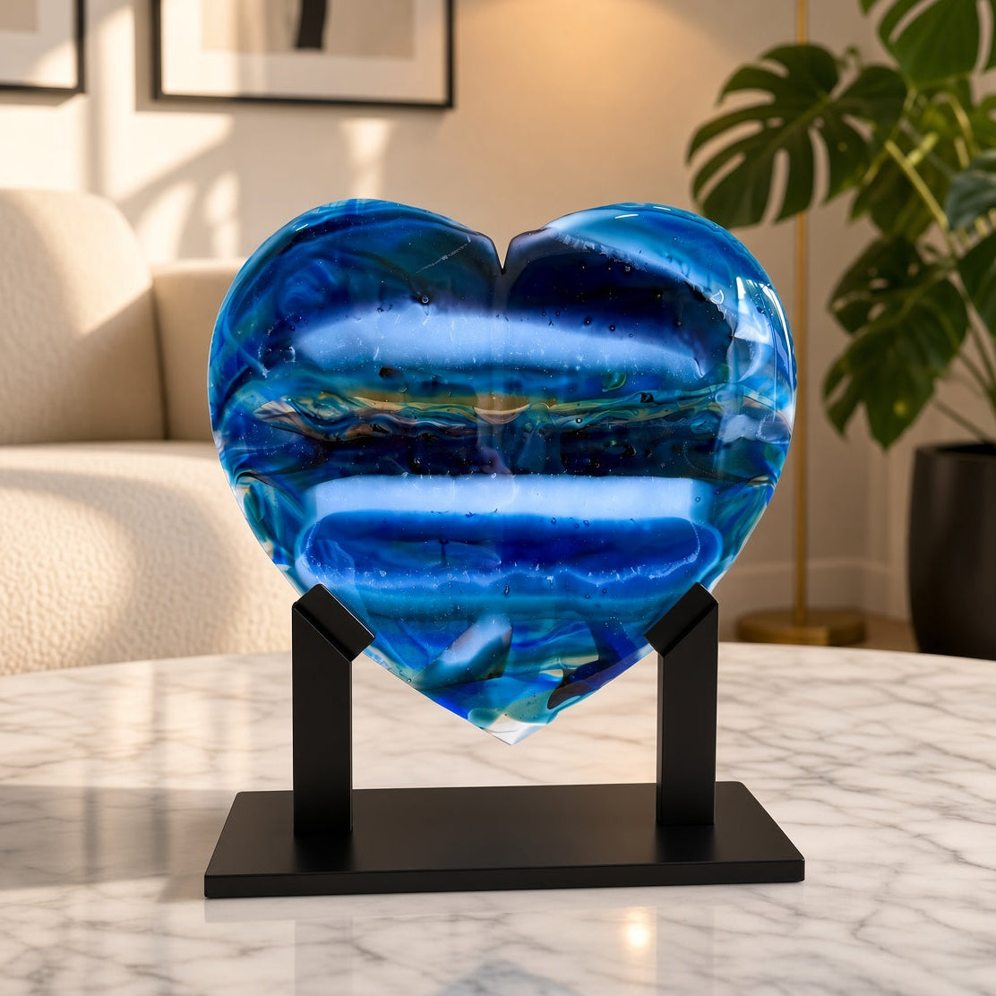 XL blue banded fused glass heart sculpture on a black stand, styled on a marble table in a modern living room — handmade art glass decor.