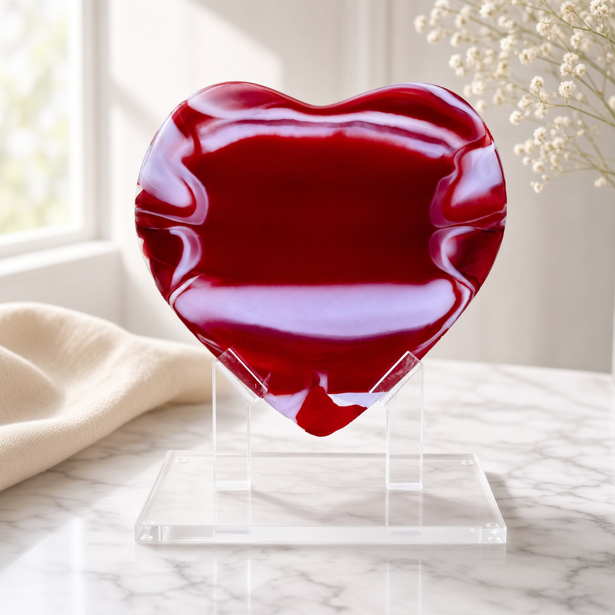 Red Glass Heart Sculpture on a clear acrylic stand on a marble surface - handmade fused art glass keepsake