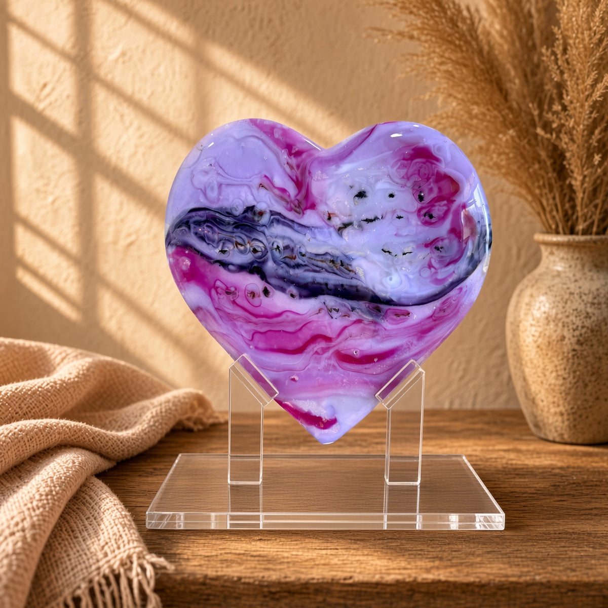 Purple, pink, white, and dark blue marbled glass heart sculpture on a clear acrylic stand on a wooden table - handmade fused art glass keepsake