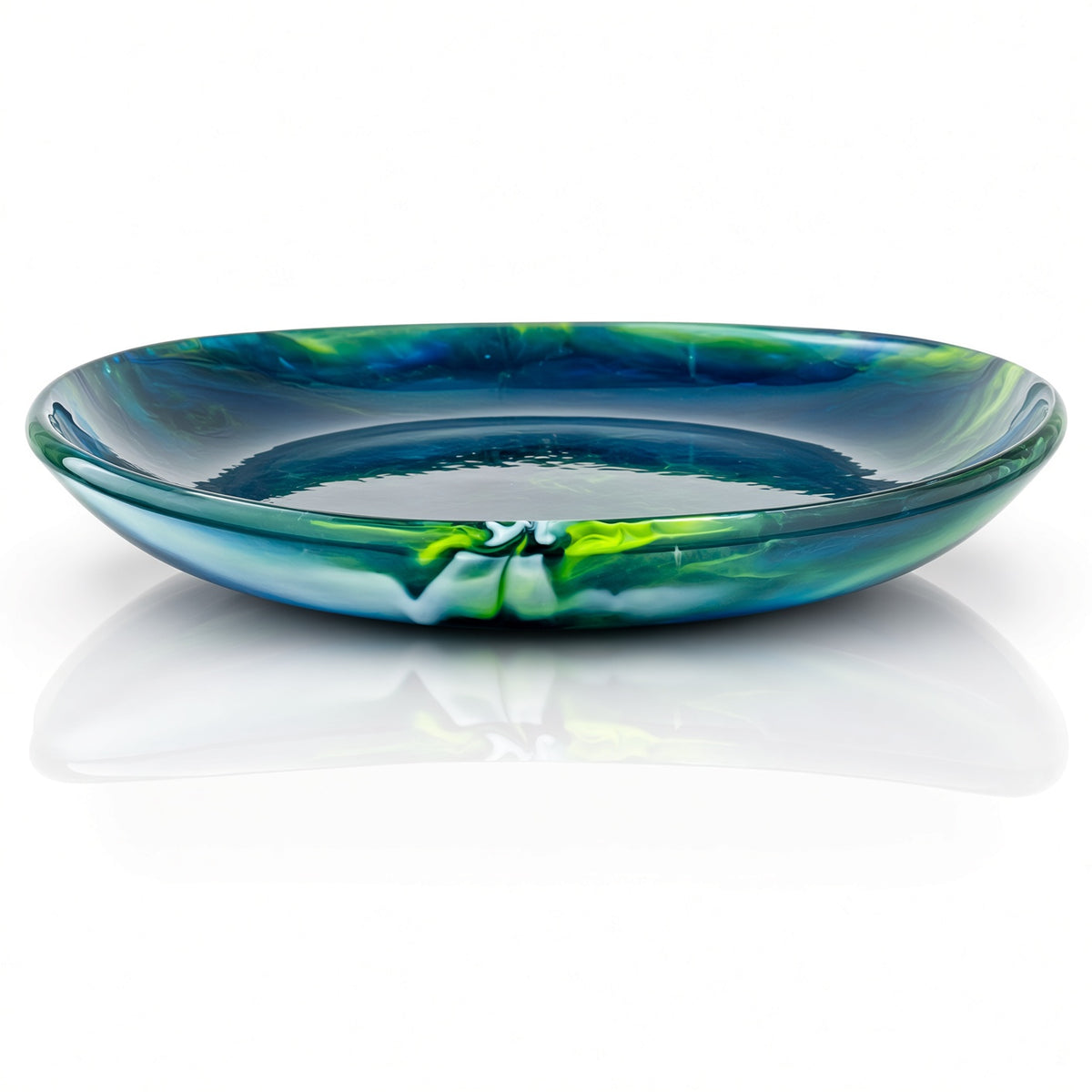 A shallow, wide glass plate with a marbled pattern of deep blue, teal, and bright green, shown on a reflective white surface.