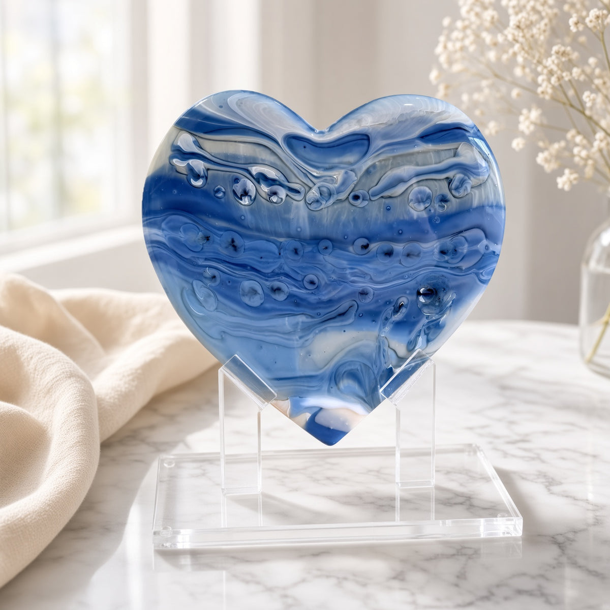 Periwinkle blue and white swirled glass heart sculpture on a clear acrylic stand on a marble surface - handmade fused art glass keepsake