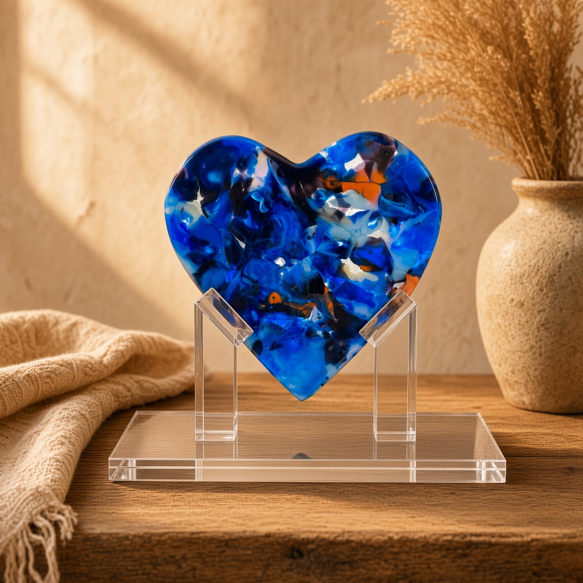 Navy blue and orange fused glass heart sculpture on clear acrylic stand, styled on a rustic wood table with vase - handmade art glass gift